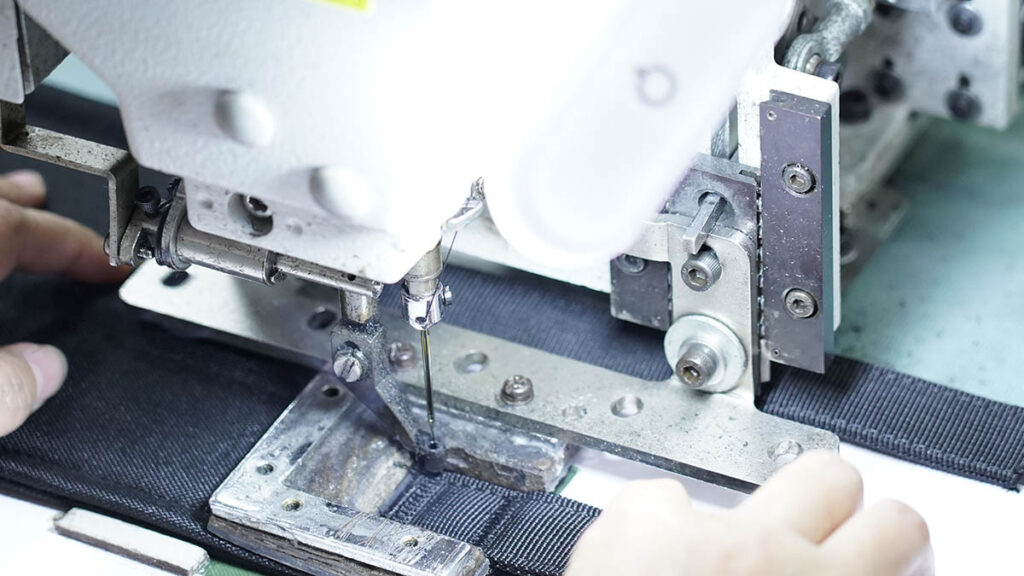 HuashengTactical reinforced Bartack stitching on a tactical vest shoulder strap stress point for enhanced load-bearing durability.